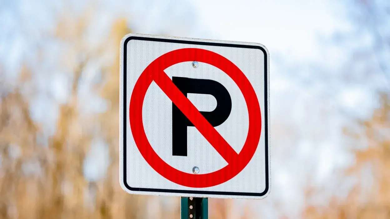 Placa de trânsito com símbolo de proibição de estacionamento, círculo vermelho com barra sobre a letra P preta.