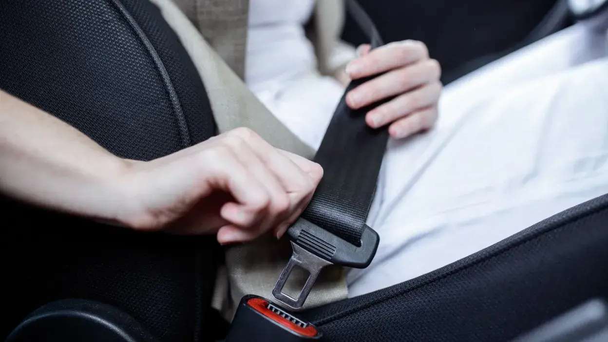 Pessoa a colocar o cinto de segurança no carro