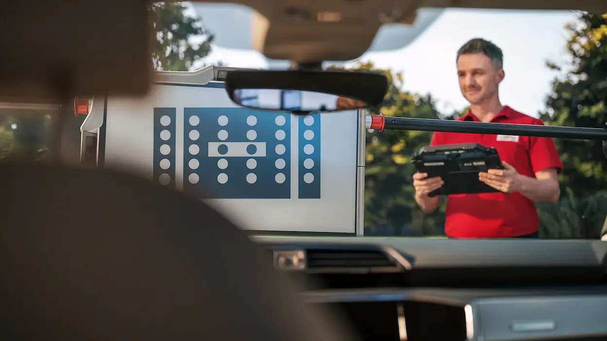 técnico da carglass a fazer a calibralão adas com máquina a um veículo