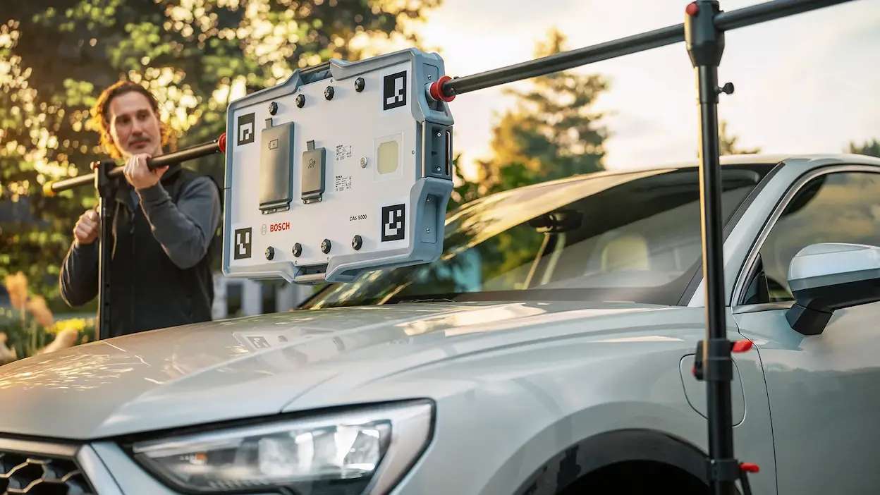 técnico da carglass a fazer a calibralão adas com máquina a um veículo estacionado na rua