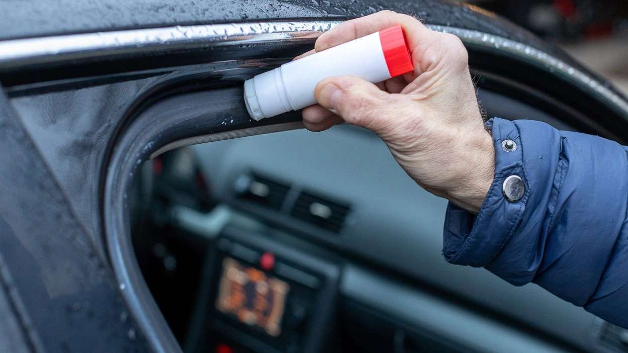 pessoa a colar a borracha da porta do carro com cola selante própria