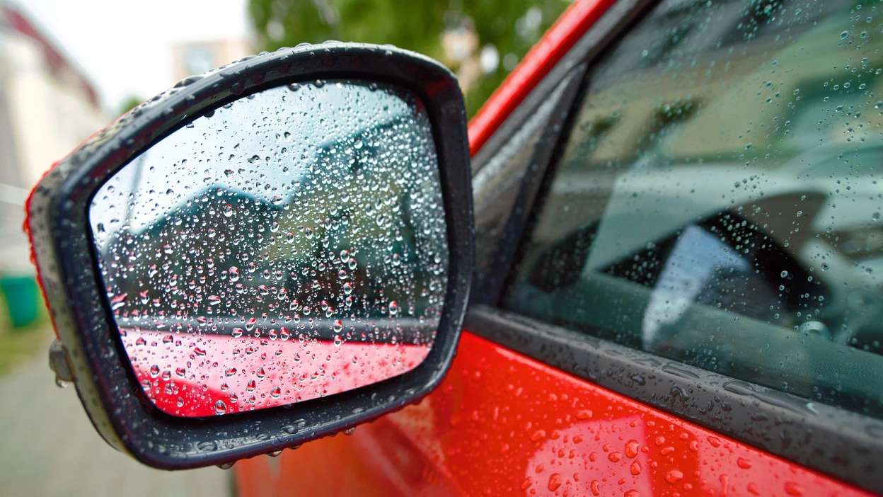 espelho retrovisor de um carro vermelho molhado com pingos da chuva