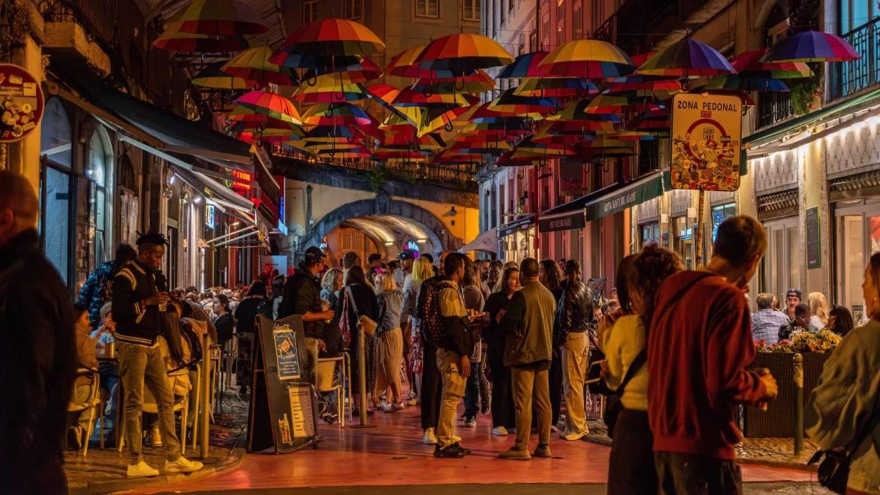 várias pessoas à noite na rua cor de rosa no cais do sodré